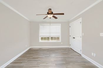 A spacious bedroom with with double window, ceiling fan, and vinyl plank flooring